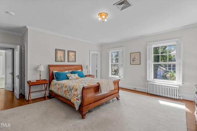 bedroom featuring hardwood / wood-style floors, crown molding, multiple windows, and radiator heating unit