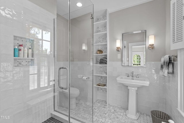 bathroom with a shower with door, toilet, tile walls, and a wealth of natural light