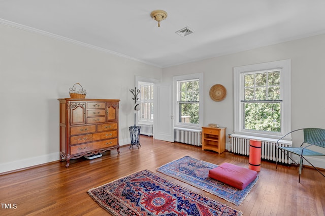 sitting room with ornamental molding, radiator heating unit, and wood-type flooring