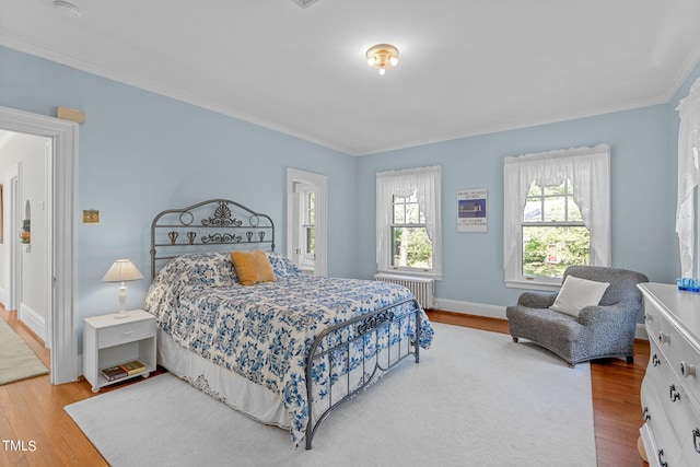 bedroom with ornamental molding, light hardwood / wood-style flooring, and radiator