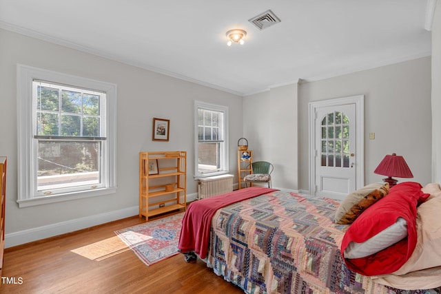 bedroom with ornamental molding, hardwood / wood-style flooring, and radiator