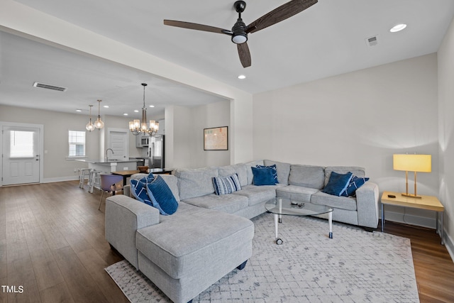 living room featuring ceiling fan with notable chandelier, hardwood / wood-style floors, and sink