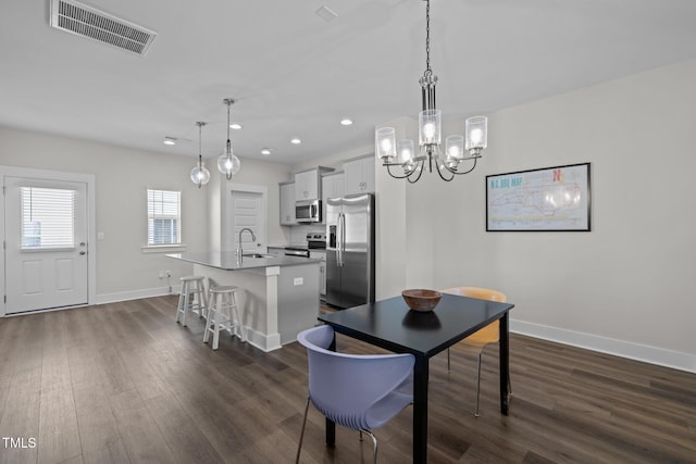 dining space featuring dark hardwood / wood-style floors, a chandelier, and sink