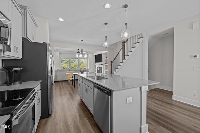 kitchen with sink, decorative light fixtures, a center island with sink, appliances with stainless steel finishes, and dark hardwood / wood-style floors