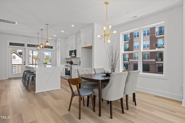 dining space featuring light hardwood / wood-style floors and a chandelier