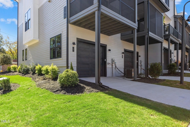 exterior space with central air condition unit, a lawn, and a garage