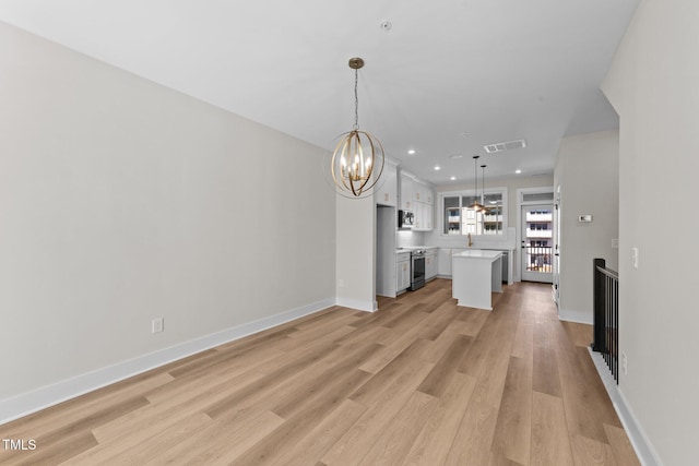 unfurnished living room featuring light wood-type flooring, sink, and a notable chandelier