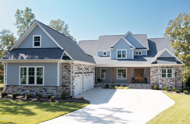 craftsman-style home featuring a garage, a porch, concrete driveway, and a front lawn