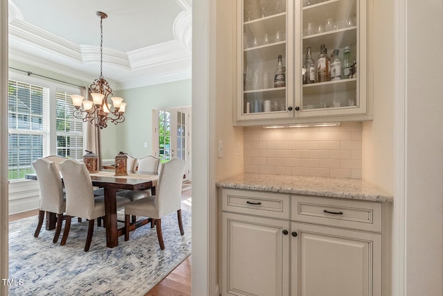 dining space with crown molding, light hardwood / wood-style flooring, a notable chandelier, and a tray ceiling