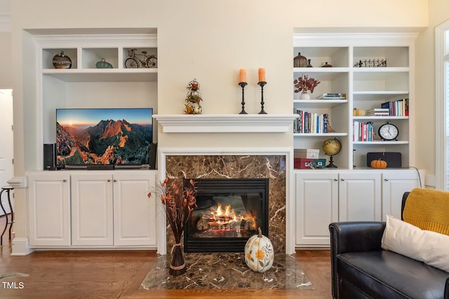 living area featuring built in features, a fireplace, and dark hardwood / wood-style floors