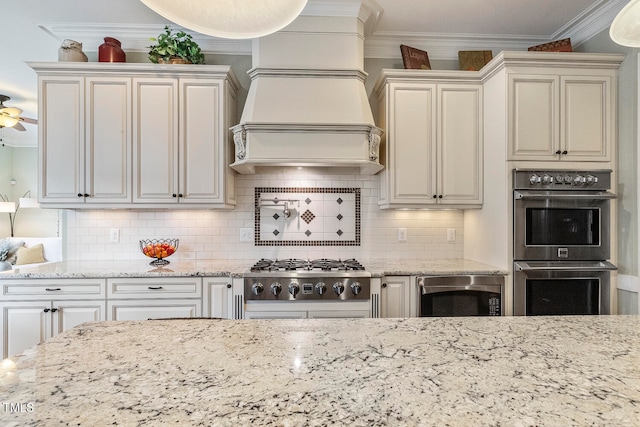 kitchen with appliances with stainless steel finishes, ceiling fan, crown molding, decorative backsplash, and premium range hood