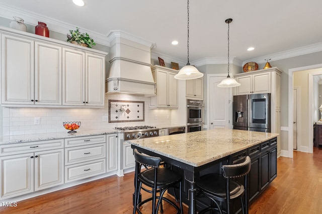 kitchen with a kitchen island, light hardwood / wood-style flooring, hanging light fixtures, stainless steel appliances, and a breakfast bar