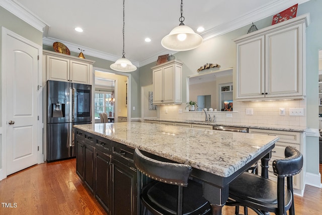 kitchen with hardwood / wood-style flooring, stainless steel appliances, ornamental molding, sink, and pendant lighting