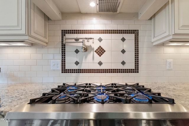 kitchen with stainless steel range, light stone countertops, and backsplash