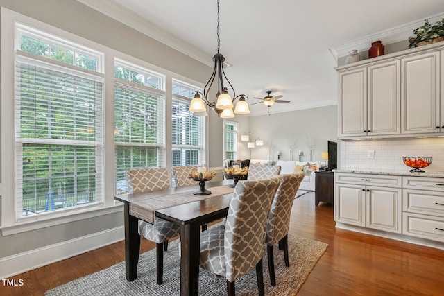 dining space with crown molding, dark hardwood / wood-style floors, a healthy amount of sunlight, and ceiling fan with notable chandelier