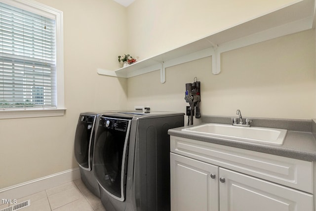 clothes washing area featuring light tile patterned flooring, sink, cabinets, and separate washer and dryer