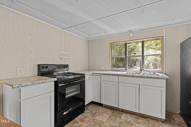 kitchen featuring light stone counters, white cabinets, sink, and electric range