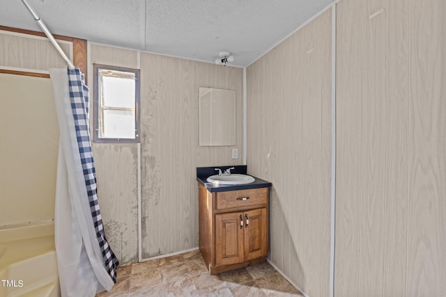 bathroom featuring vanity, wooden walls, and a textured ceiling