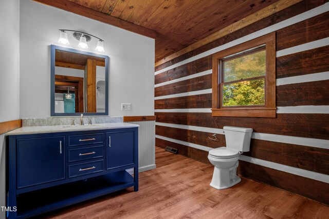 bathroom with wood walls, wood-type flooring, toilet, wooden ceiling, and vanity