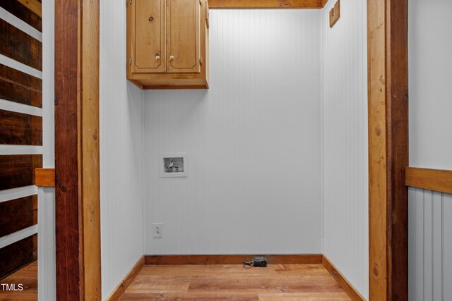 clothes washing area featuring hookup for a washing machine, light hardwood / wood-style floors, and cabinets