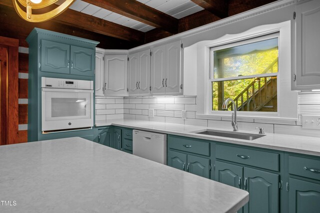 kitchen featuring beam ceiling, backsplash, sink, white cabinets, and white appliances