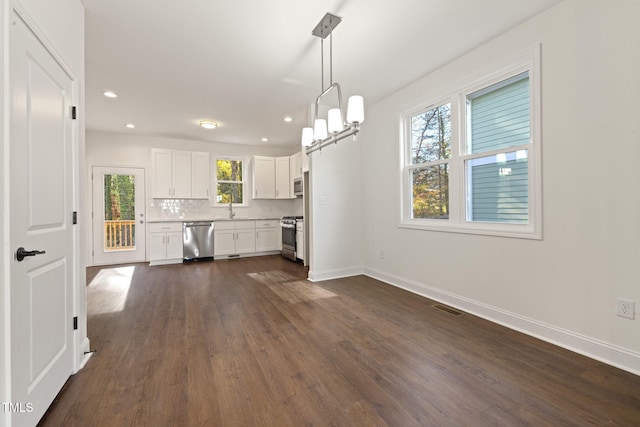 kitchen featuring plenty of natural light, white cabinets, stainless steel appliances, and decorative light fixtures