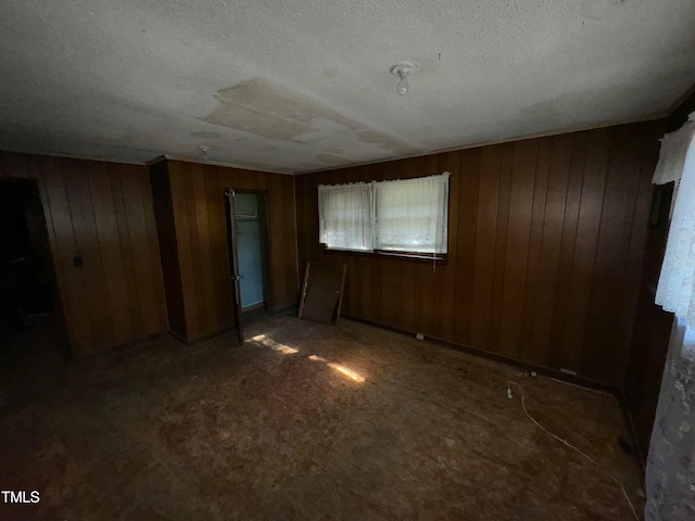 empty room with wooden walls and a textured ceiling