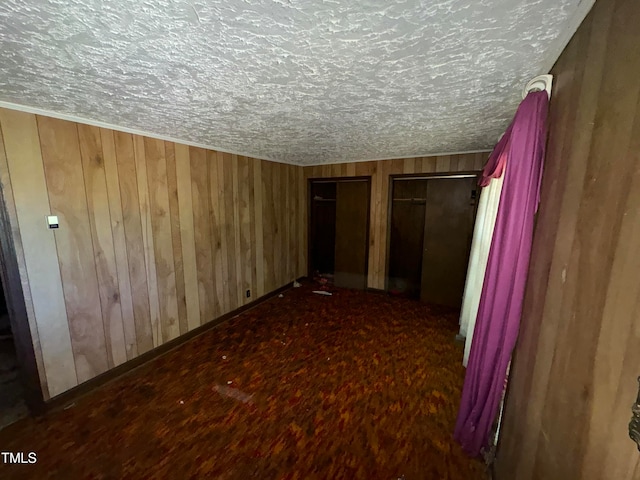 interior space featuring wood-type flooring, wooden walls, and a textured ceiling