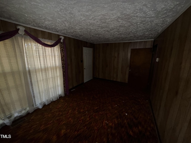 empty room with wood walls, dark hardwood / wood-style flooring, and a textured ceiling