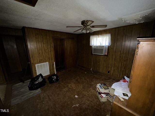 unfurnished bedroom featuring ceiling fan, a closet, cooling unit, wood walls, and a textured ceiling