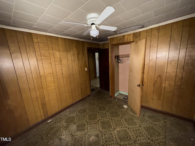 interior space with a closet, wooden walls, and ceiling fan