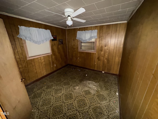 empty room with wood walls, ornamental molding, and ceiling fan