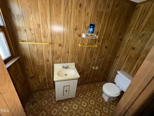 bathroom featuring wooden walls, toilet, and vanity