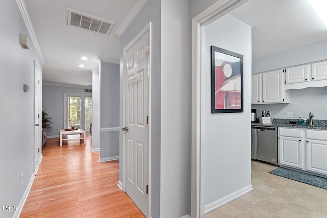 hall with light wood-type flooring, sink, and crown molding