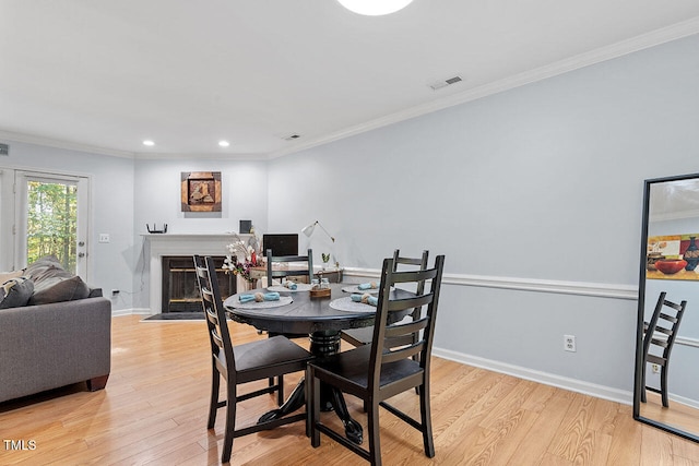 dining area with ornamental molding and light hardwood / wood-style flooring