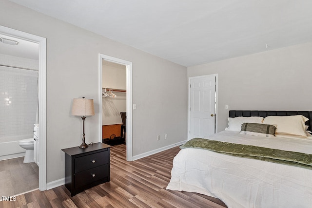 bedroom with ensuite bathroom, wood-type flooring, a closet, and a walk in closet