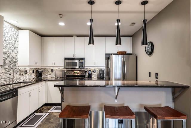 kitchen with white cabinets, appliances with stainless steel finishes, decorative light fixtures, and sink