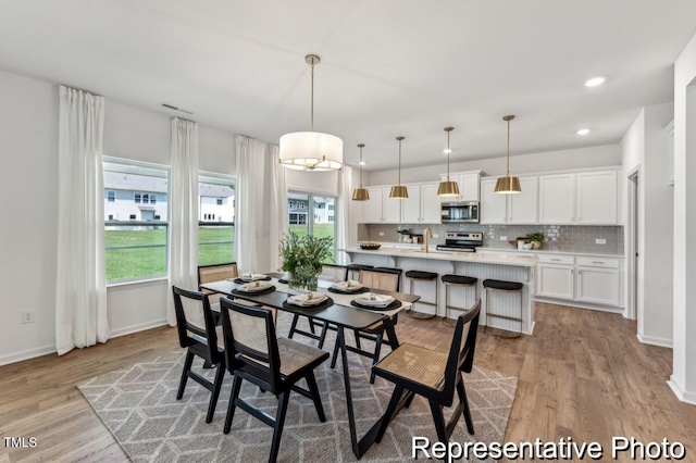 dining room featuring light wood-type flooring, sink, and a wealth of natural light