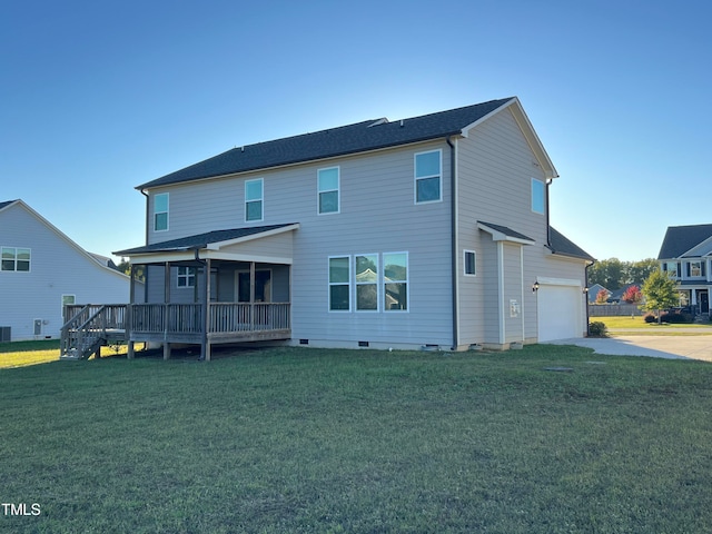 rear view of property with a garage, a deck, and a yard