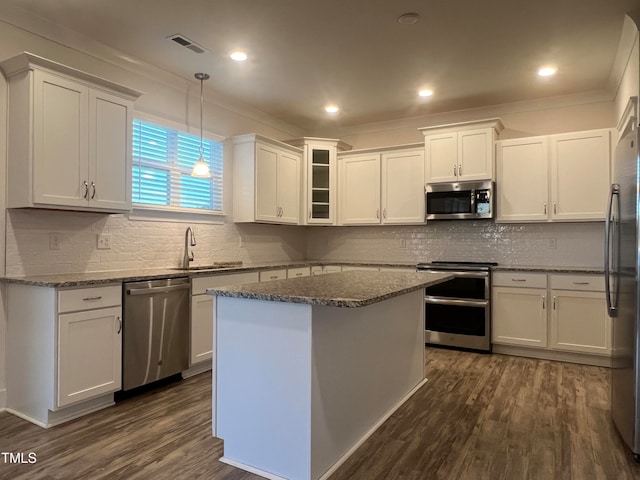 kitchen featuring pendant lighting, stainless steel appliances, dark wood-type flooring, and white cabinetry