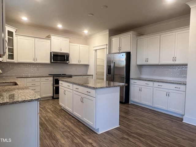 kitchen with appliances with stainless steel finishes, tasteful backsplash, dark wood-type flooring, and white cabinets