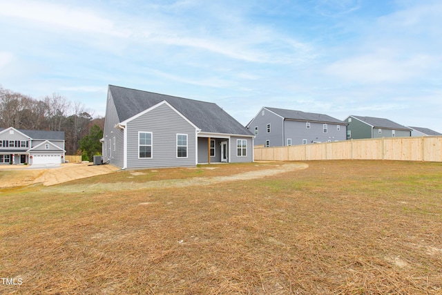 back of property featuring a garage, cooling unit, and a lawn