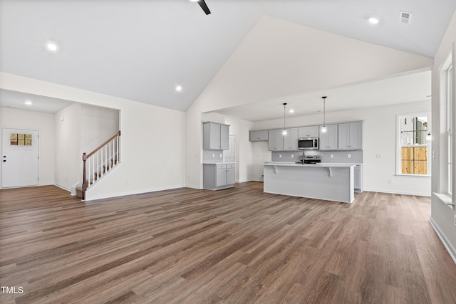 unfurnished living room featuring wood-type flooring and high vaulted ceiling