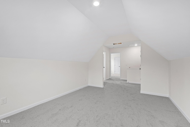 bonus room with light colored carpet and vaulted ceiling