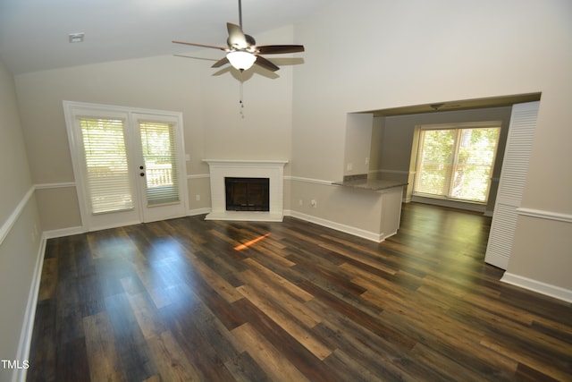 unfurnished living room with a healthy amount of sunlight, ceiling fan, dark wood-type flooring, and high vaulted ceiling