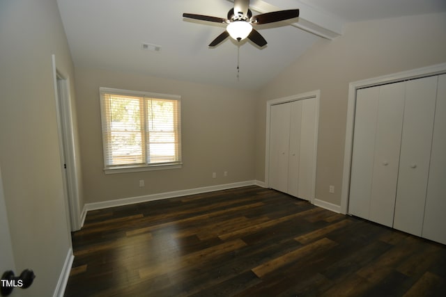 unfurnished bedroom with lofted ceiling with beams, two closets, ceiling fan, and dark hardwood / wood-style floors