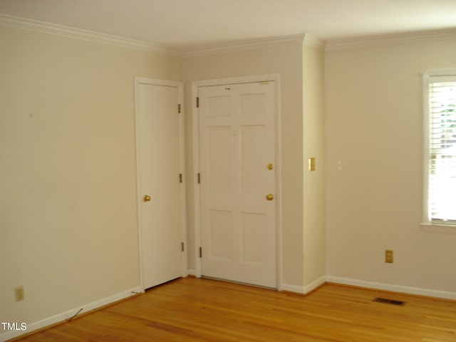 unfurnished room with ornamental molding and light wood-type flooring