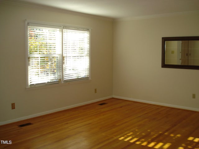 spare room with ornamental molding and hardwood / wood-style flooring