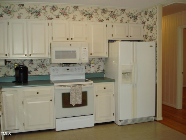 kitchen with white appliances, ornamental molding, and white cabinets