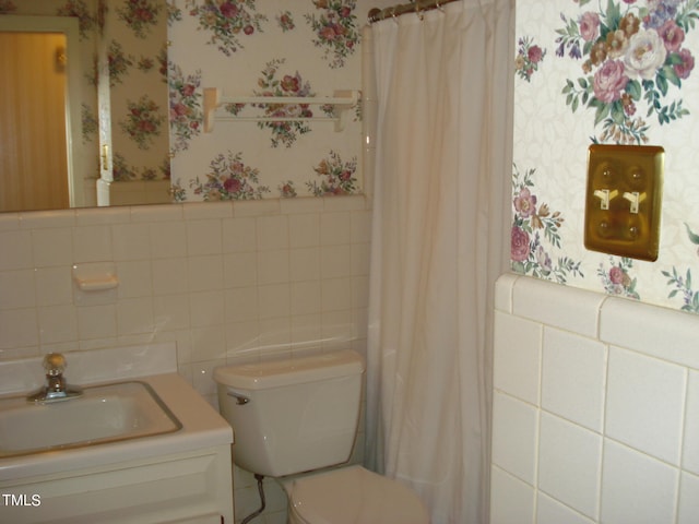 bathroom with walk in shower, vanity, tile walls, and toilet